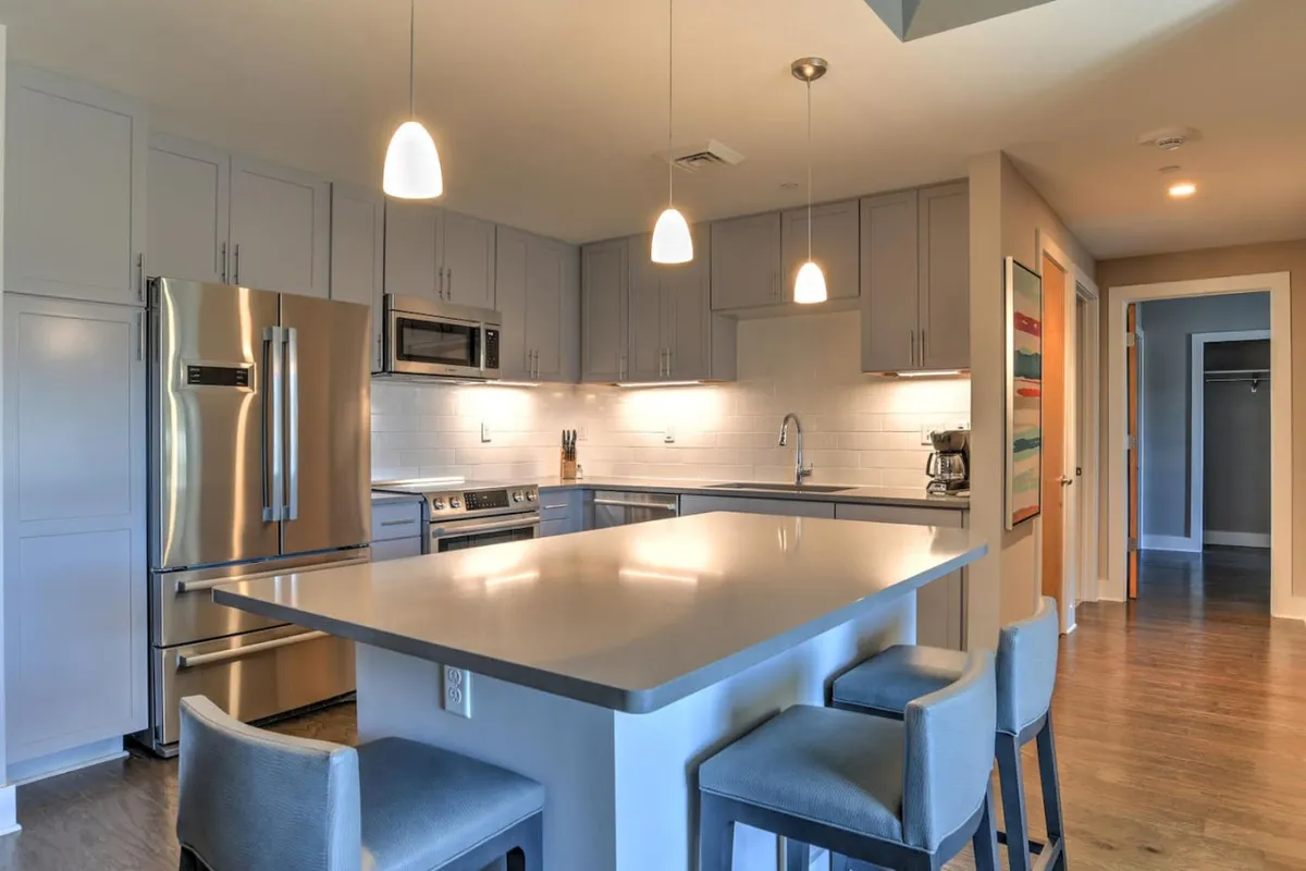 A modern kitchen featuring an island countertop, stainless steel appliances, pendant lighting, and a stylish backsplash. The space is both functional and inviting, ideal for cooking, casual dining, and hosting friends or family.